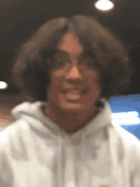 a man wearing glasses and a white hoodie looks at the camera