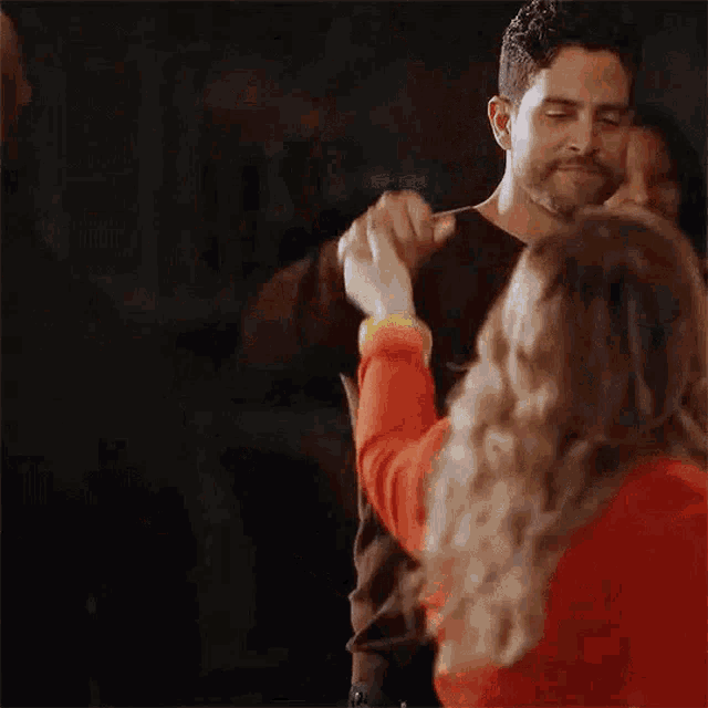 a man and a woman are dancing together and the woman is holding the man 's arm .
