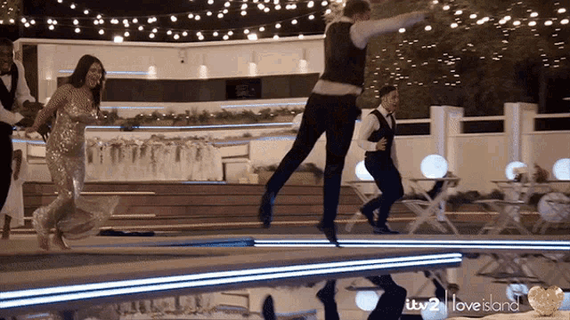 a group of people dancing in front of a love island logo
