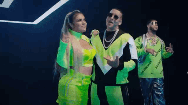 two men and a woman are standing next to each other in neon green outfits .