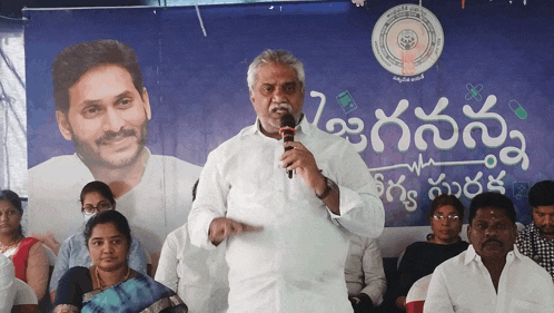a man speaks into a microphone in front of a sign that says ' telugu '
