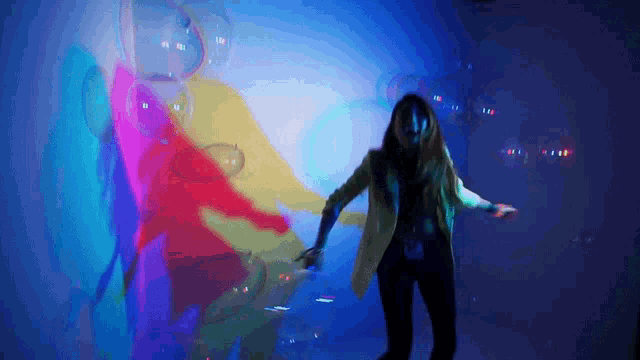a woman is dancing in front of a colorful display