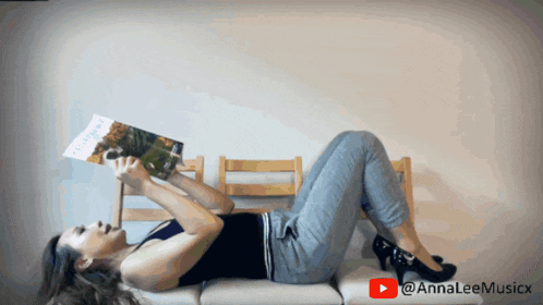 a woman is laying on her stomach reading a book with a youtube logo behind her