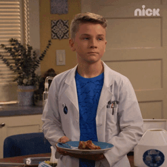 a young boy in a lab coat holds a plate of food in his hands