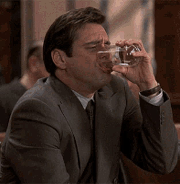 a man in a suit and tie is splashing water into his face