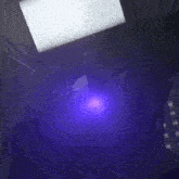 a purple light is shining on a laptop in the dark .