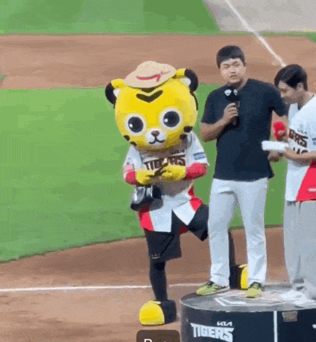 a mascot for the tigers is standing on a podium on a baseball field .