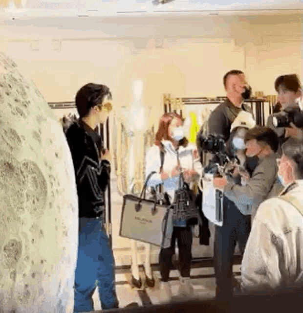 a group of people are standing in a store talking to each other while wearing face masks .