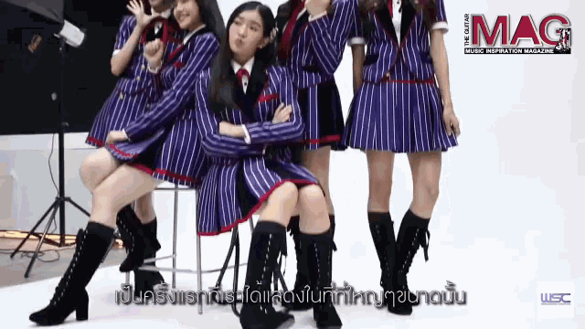 a group of girls standing next to each other with a mag magazine behind them