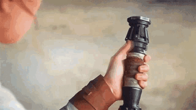 a person is holding a star wars lightsaber in their hand .