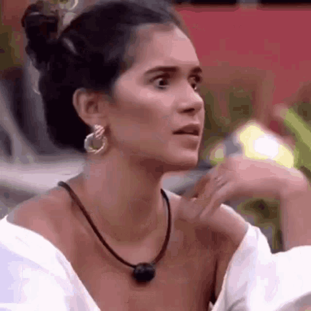 a woman wearing a white shirt and a necklace is making a funny face .