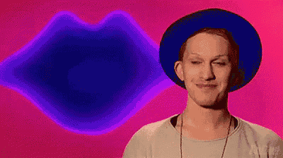 a man wearing a blue hat is smiling in front of a pink background with a purple lip .