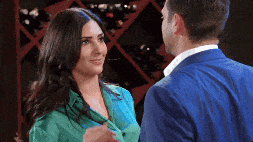 a man in a suit and a woman in a green shirt are standing next to each other