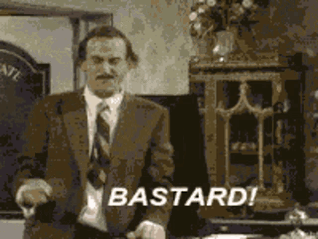 a man in a suit and tie is standing in front of a sign that reads bastard
