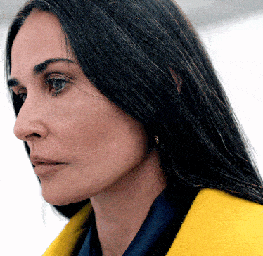 a close up of a woman 's face with a yellow coat