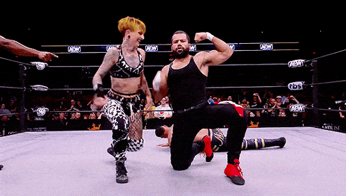 a man and a woman are posing in a wrestling ring that says aew on the side