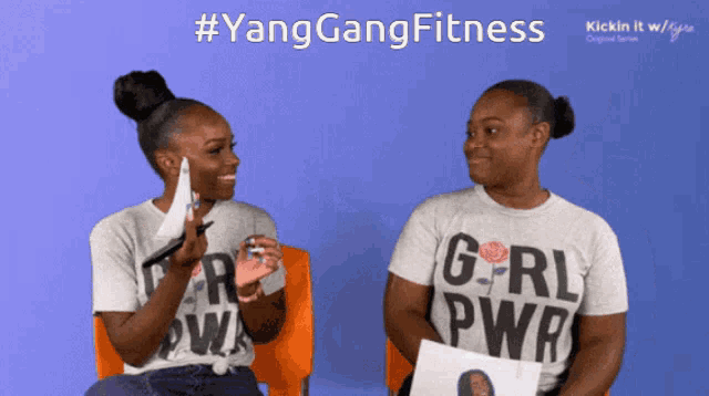 two women wearing girl power shirts are sitting next to each other on a blue background