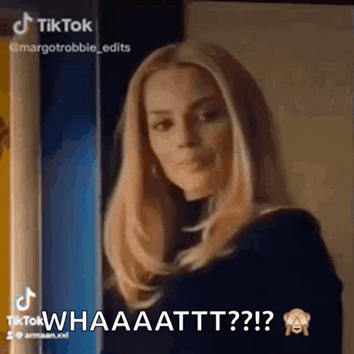 a woman with blonde hair is standing in front of a door and says " whaaattttt "