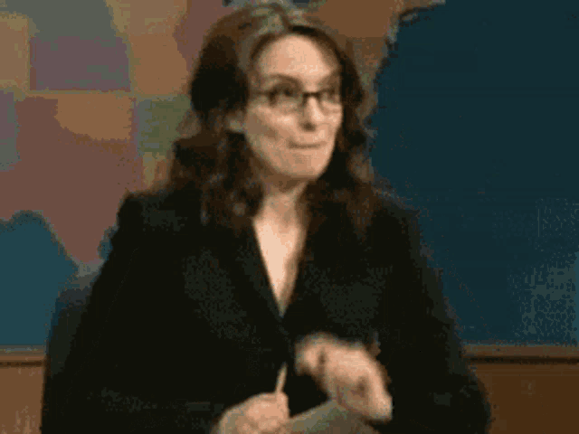 a woman wearing glasses and a black suit stands in front of a map of the united states .