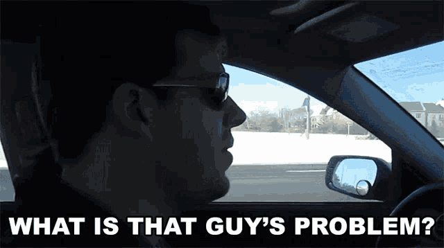 a man driving a car with the words what is that guy 's problem