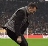 a man is standing on a soccer field in front of a crowd .