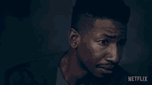 a close up of a man 's face in a dark room with a netflix logo in the corner .