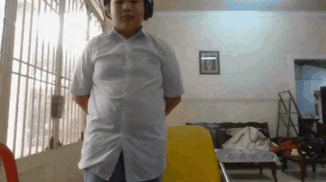 a man wearing headphones and a white shirt stands in a room