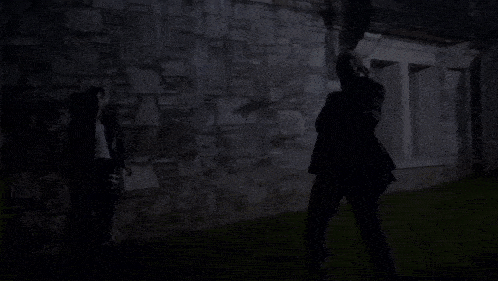 two people standing in front of a stone wall