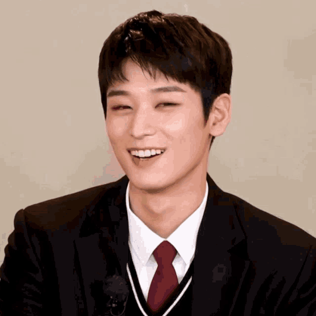 a man in a suit and tie is smiling with a yellow r on his forehead