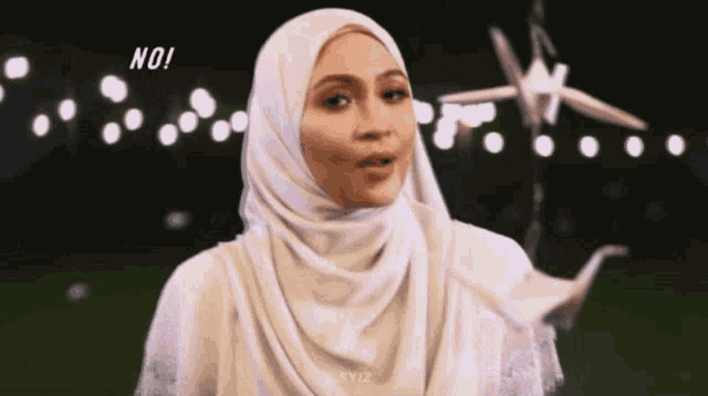 a woman wearing a white hijab is standing in front of a plane flying in the sky .