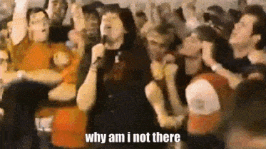 a man singing into a microphone in front of a crowd with the words " why am i not there "
