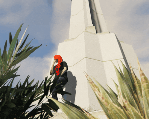 a person with a red scarf around their head is standing in front of a tall white building
