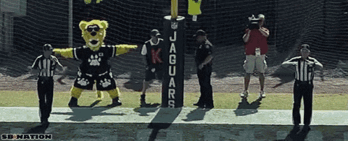 a jaguars mascot stands next to a referee on the field