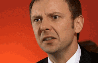 a man in a suit and tie is making a funny face in front of a red wall .