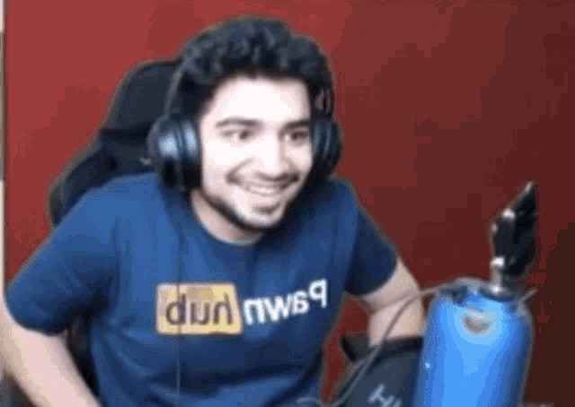 a man wearing headphones and a pornhub shirt is sitting in a chair .