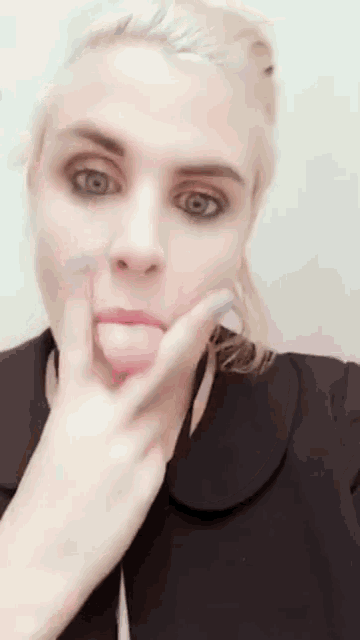 a woman is sticking her tongue out while wearing a black top
