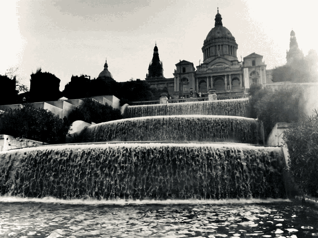 a waterfall with a large building in the background
