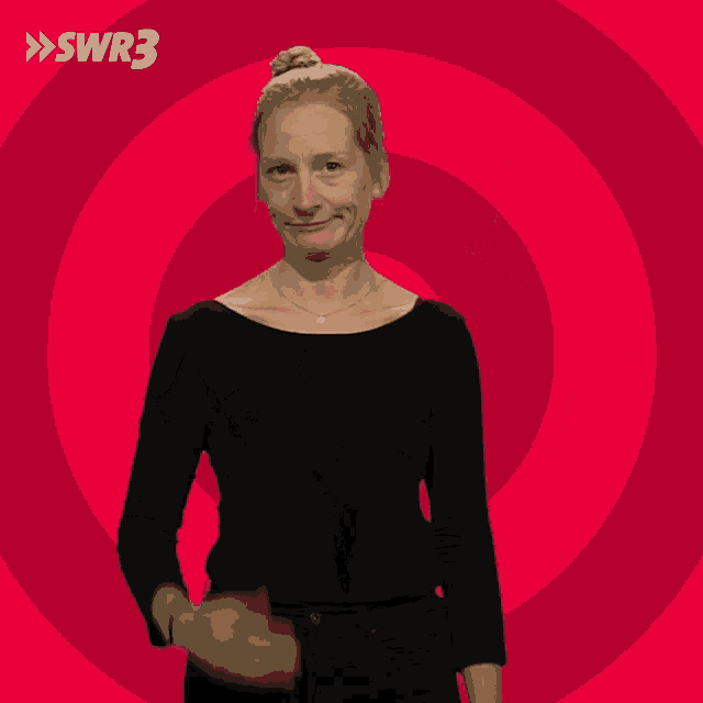 a woman in a black shirt stands in front of a red swirl with swr3 on the bottom