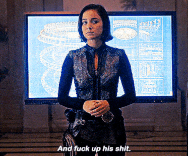 a woman is standing in front of a large screen that says and fuck up his shit .