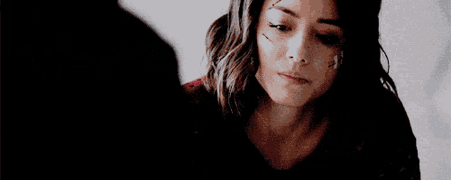 a woman with a scar on her forehead is looking down at something .