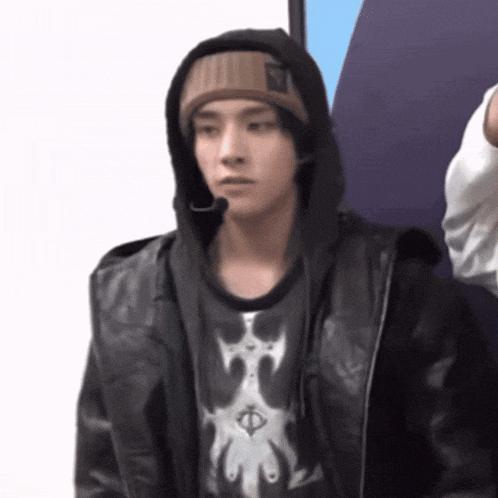 a man wearing a hooded jacket and a beanie looks at the camera