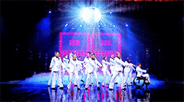 a group of people dancing on a stage with a disco ball