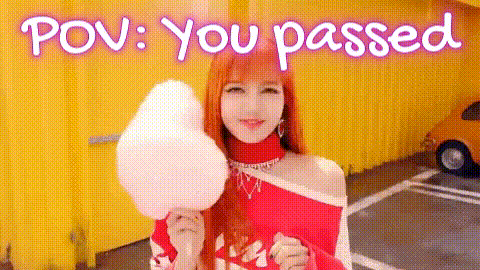 a woman is holding a piece of cotton candy in front of a yellow building .