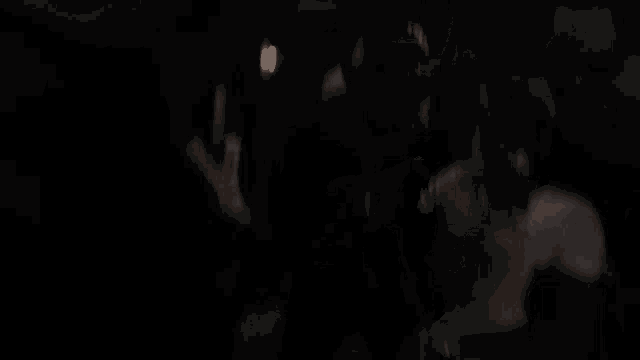a man in a gas mask stands in a dark room with other people