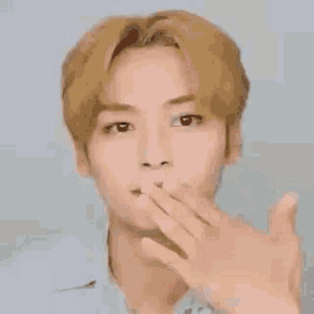 a close up of a person blowing a kiss with their hands .