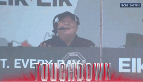 a man wearing a headset stands in front of a sign that says cbs big ten