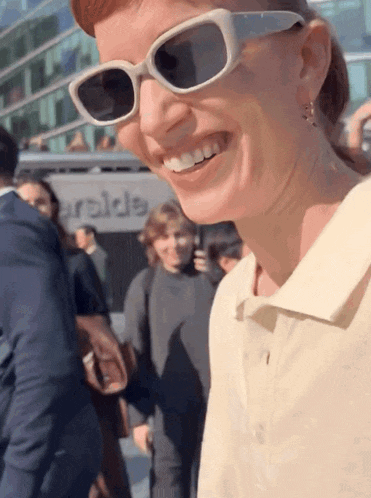 a woman wearing sunglasses smiles in front of a building that says ' arabia '