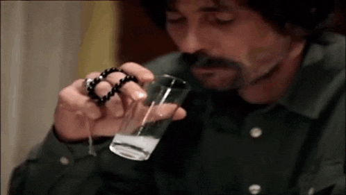 a man is holding a glass of water and a rosary .