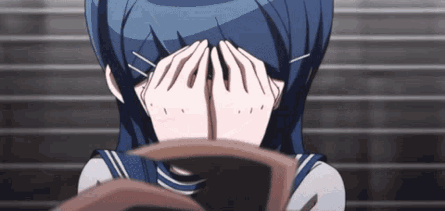 a girl in a school uniform is covering her face with her hands .