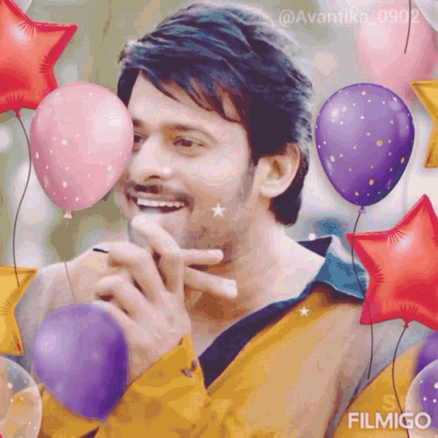 a man in a yellow shirt is surrounded by balloons and stars .